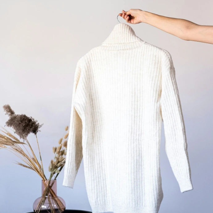 a white sweater hanging on a clothes rack